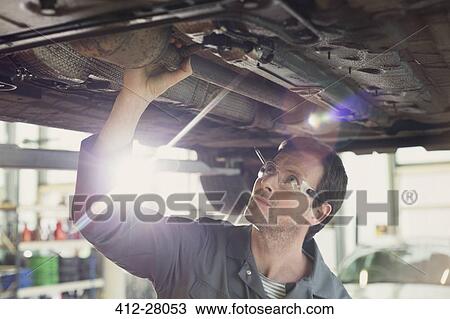 Mechanic working under car in auto repair shop View Large Photo Image Stock Image - Mechanic working under car in auto repair shop. Fotosearch
