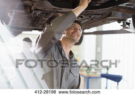 Stock Photo - Mechanic working under car in auto repair shop. Fotosearch