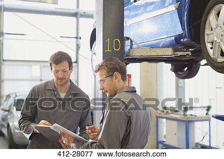 Mechanics reviewing paperwork in auto repair shop View Large Photo Image Stock Photo - Mechanics reviewing paperwork in auto repair shop. Fotosearch