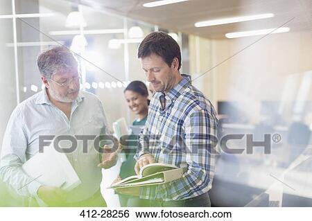 Stock Photograph - Men discussing book in adult education classroom. Fotosearch