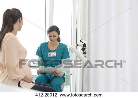 Nurse and pregnant patient reviewing medical chart in examination room View Large Photo Image Stock Image - Nurse and pregnant patient reviewing medical chart in examination room. Fotosearch
