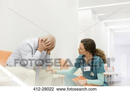 Nurse consoling upset man in clinic corridor View Large Photo Image Stock Image - Nurse consoling upset man in clinic corridor. Fotosearch