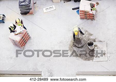 Overhead view of construction workers laying concrete at construction site View Large Photo Image Stock Photo - Overhead view of construction workers laying concrete at construction site. Fotosearch
