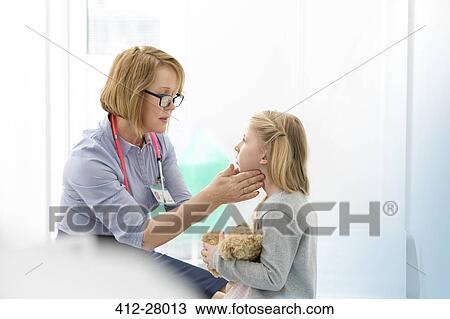 Stock Image - Pediatrician checking girl patient’s glands in examination room. Fotosearch