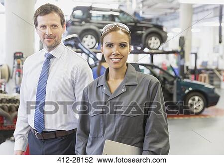 Stock Image - Portrait confident businessman and female mechanic in auto repair shop. Fotosearch