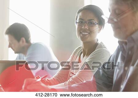 Stock Image - Portrait confident businesswoman at laptop in meeting. Fotosearch