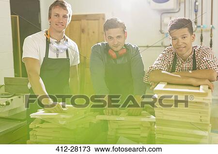 Stock Image - Portrait confident carpenters with stacks of wood in workshop. Fotosearch
