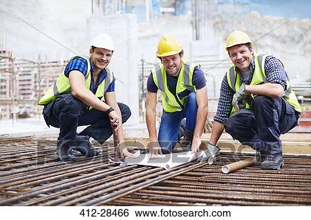 Stock Photograph - Portrait confident construction workers and engineer reviewing blueprint at construction site. Fotosearch