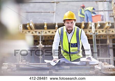 Portrait confident engineer with blueprints at construction site View Large Photo Image Stock Image - Portrait confident engineer with blueprints at construction site. Fotosearch