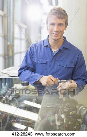Stock Image - Portrait confident mechanic working on engine in auto repair shop. Fotosearch
