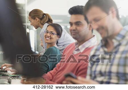 Stock Image - Portrait confident woman at computer in adult education classroom. Fotosearch