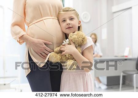 Portrait girl with teddy bear hugging pregnant mother in doctor’s office View Large Photo Image Picture - Portrait girl with teddy bear hugging pregnant mother in doctor’s office. Fotosearch