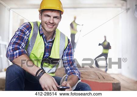 Portrait smiling construction worker with cell phone at construction site View Large Photo Image Picture - Portrait smiling construction worker with cell phone at construction site. Fotosearch