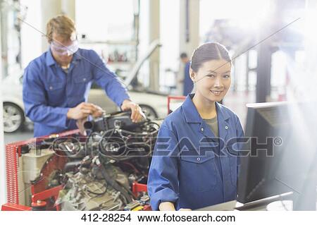 Picture - Portrait smiling female mechanic at computer in auto repair shop. Fotosearch