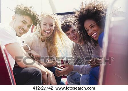 Stock Image - Portrait smiling friends riding double-decker bus. Fotosearch