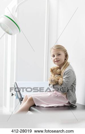 Portrait smiling girl patient hugging teddy bear in examination room View Large Photo Image Stock Photo - Portrait smiling girl patient hugging teddy bear in examination room. Fotosearch