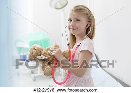 Portrait smiling girl using stethoscope on teddy bear in examination room View Large Photo Image Stock Photograph - Portrait smiling girl using stethoscope on teddy bear in examination room. Fotosearch