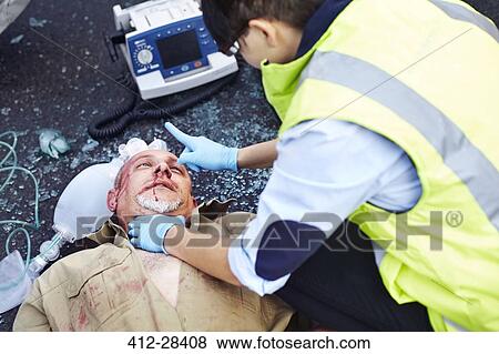 Rescue worker tending to car accident victim in road View Large Photo Image Stock Photo - Rescue worker tending to car accident victim in road. Fotosearch