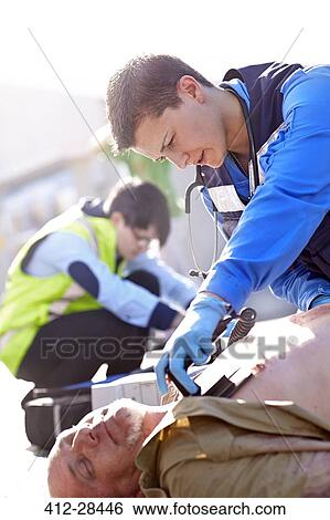 Rescue worker using defibrillator on unconscious car accident victim in road View Large Photo Image Stock Photograph - Rescue worker using defibrillator on unconscious car accident victim in road. Fotosearch