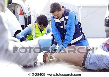 Rescue workers performing CPR on car accident victim in road View Large Photo Image Stock Photo - Rescue workers performing CPR on car accident victim in road. Fotosearch