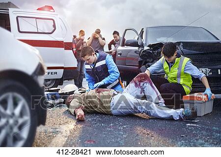 Rescue workers tending to bloody car accident victim in road View Large Photo Image Stock Image - Rescue workers tending to bloody car accident victim in road. Fotosearch