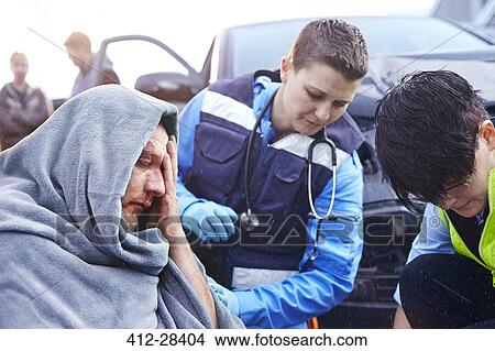 Picture - Rescue workers tending to car accident victim. Fotosearch