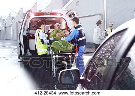 Rescue workers tending to car accident victim on stretcher at back of ambulance View Large Photo Image Picture - Rescue workers tending to car accident victim on stretcher at back of ambulance. Fotosearch