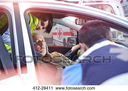 Rescue workers tending to car accident victim in car View Large Photo Image Stock Image - Rescue workers tending to car accident victim in car. Fotosearch