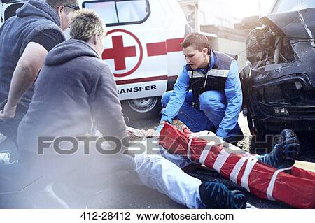 Rescue workers tending to car accident victim in road View Large Photo Image Stock Image - Rescue workers tending to car accident victim in road. Fotosearch