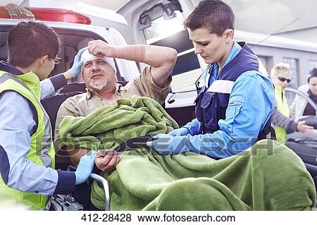 Rescue workers tending to car accident victim on stretcher at back of ambulance View Large Photo Image Stock Photo - Rescue workers tending to car accident victim on stretcher at back of ambulance. Fotosearch