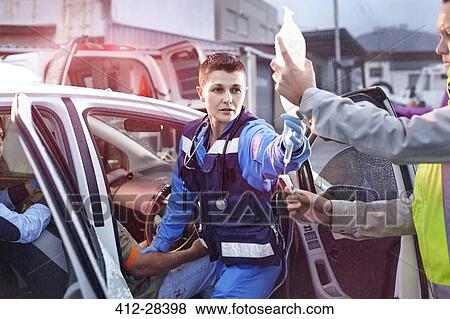 Stock Photo - Rescue workers with IV bag tending to car accident victim. Fotosearch