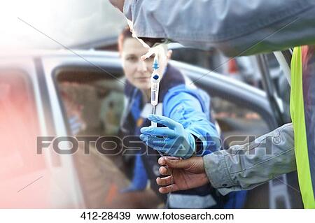 Rescue workers with IV drip tending to car accident victim in car View Large Photo Image Stock Photo - Rescue workers with IV drip tending to car accident victim in car. Fotosearch