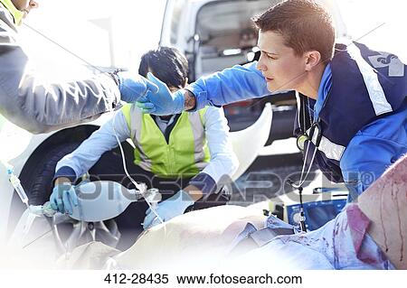 Rescue workers with manual resuscitator over car accident victim in road View Large Photo Image Stock Photography - Rescue workers with manual resuscitator over car accident victim in road. Fotosearch