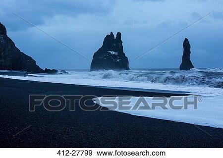 Stock Photo - Rock formations and stormy ocean at dusk, Reynisdrangar, Vik, Iceland. Fotosearch