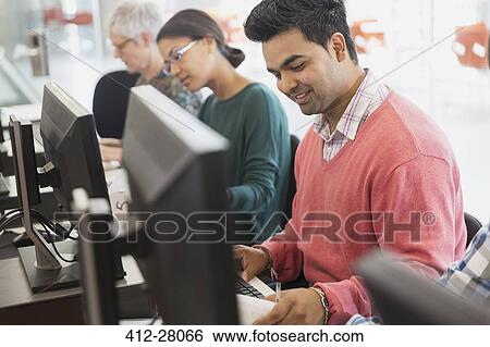 Stock Photograph - Smiling adult education student at computer in classroom. Fotosearch
