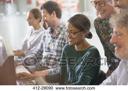 Smiling adult education students working together at computer in classroom View Large Photo Image Stock Image - Smiling adult education students working together at computer in classroom. Fotosearch