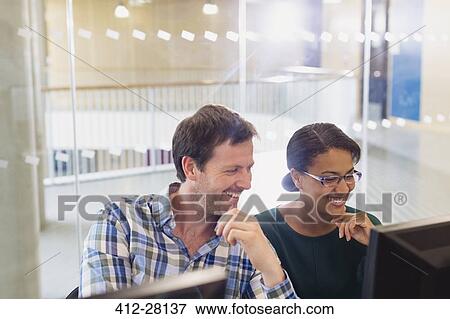 Smiling businessman and businesswoman working at computer in office View Large Photo Image Stock Photo - Smiling businessman and businesswoman working at computer in office. Fotosearch