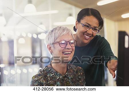 Stock Photograph - Smiling businesswomen at computer in office. Fotosearch