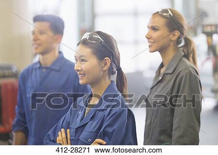 Smiling mechanics looking away in auto repair shop View Large Photo Image Stock Image - Smiling mechanics looking away in auto repair shop. Fotosearch