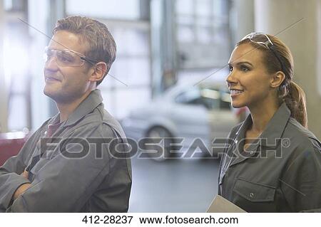 Smiling mechanics looking away in auto repair shop View Large Photo Image Stock Photo - Smiling mechanics looking away in auto repair shop. Fotosearch
