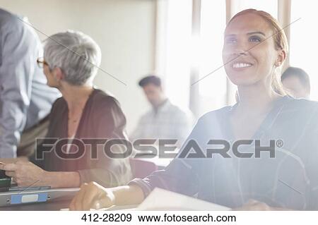 Stock Photo - Smiling woman in sunny adult education workshop. Fotosearch