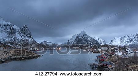 Picture - Snow covered mountain range above fishing village at dusk, Reine, Lofoten Islands, Norway. Fotosearch