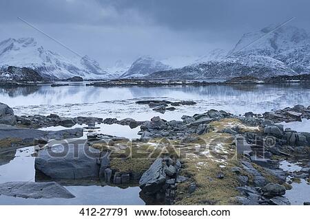 Snow covered mountains behind cold calm bay, Lofoten Islands, Norway View Large Photo Image Stock Image - Snow covered mountains behind cold calm bay, Lofoten Islands, Norway. Fotosearch
