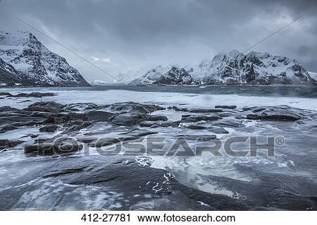 Snow covered mountains behind cold ocean, Vareid, Lofoten Islands, Norway View Large Photo Image Stock Image - Snow covered mountains behind cold ocean, Vareid, Lofoten Islands, Norway. Fotosearch