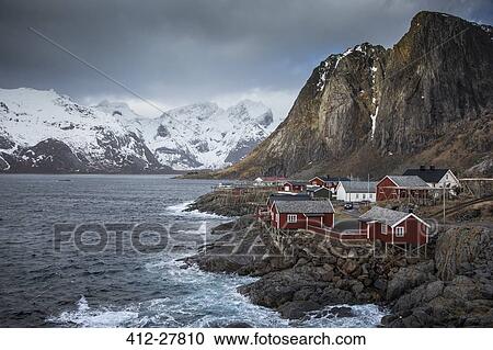 Snow covered mountains behind craggy fishing village on bay, Hamnoya, Lofoten Islands, Norway View Large Photo Image Stock Image - Snow covered mountains behind craggy fishing village on bay, Hamnoya, Lofoten Islands, Norway. Fotosearch