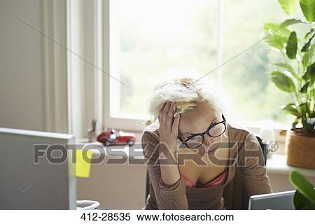 Stressed woman with hands in hair working in office View Large Photo Image Stock Photography - Stressed woman with hands in hair working in office. Fotosearch
