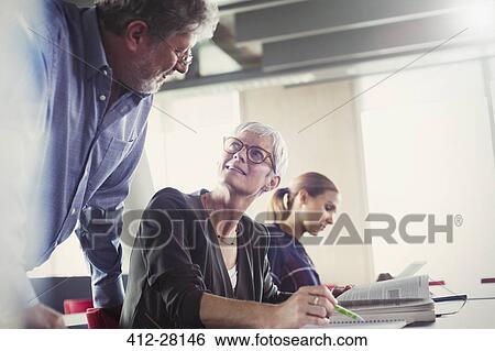 Stock Photograph - Students discussing homework in adult education classroom. Fotosearch