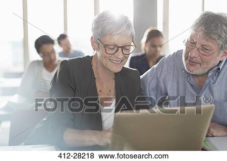 Stock Photo - Students studying at laptop in adult education classroom. Fotosearch