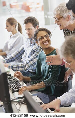 Stock Photo - Students talking at computers in adult education classroom. Fotosearch