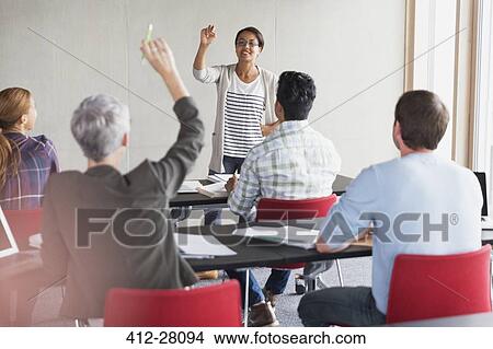 Teacher calling on student with hand raised in adult education classroom View Large Photo Image Picture - Teacher calling on student with hand raised in adult education classroom. Fotosearch